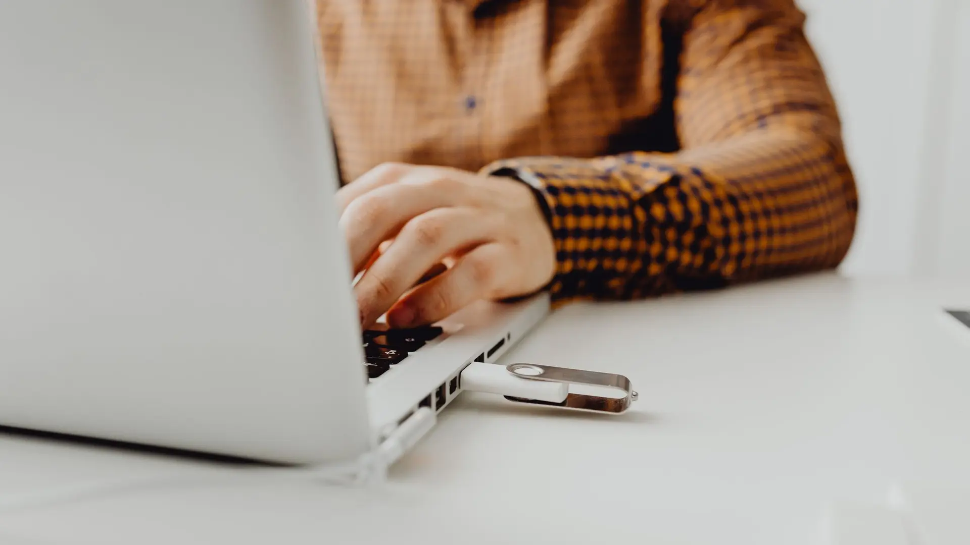 A USB flash drive connected to a laptop representing an account data export
