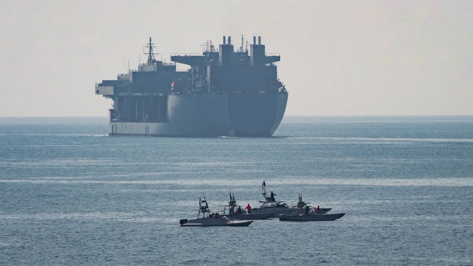 A U.S. Navy support ship transits the Strait of Hormuz under a clear sky