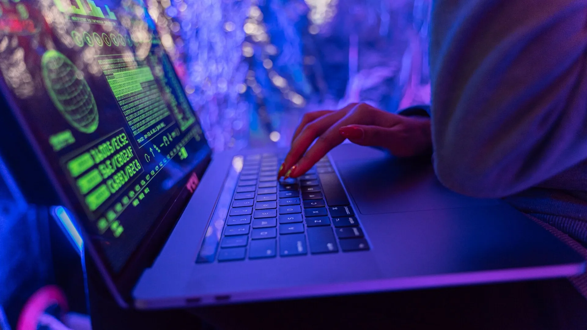 Hands typing on a laptop displaying cybersecurity graphics