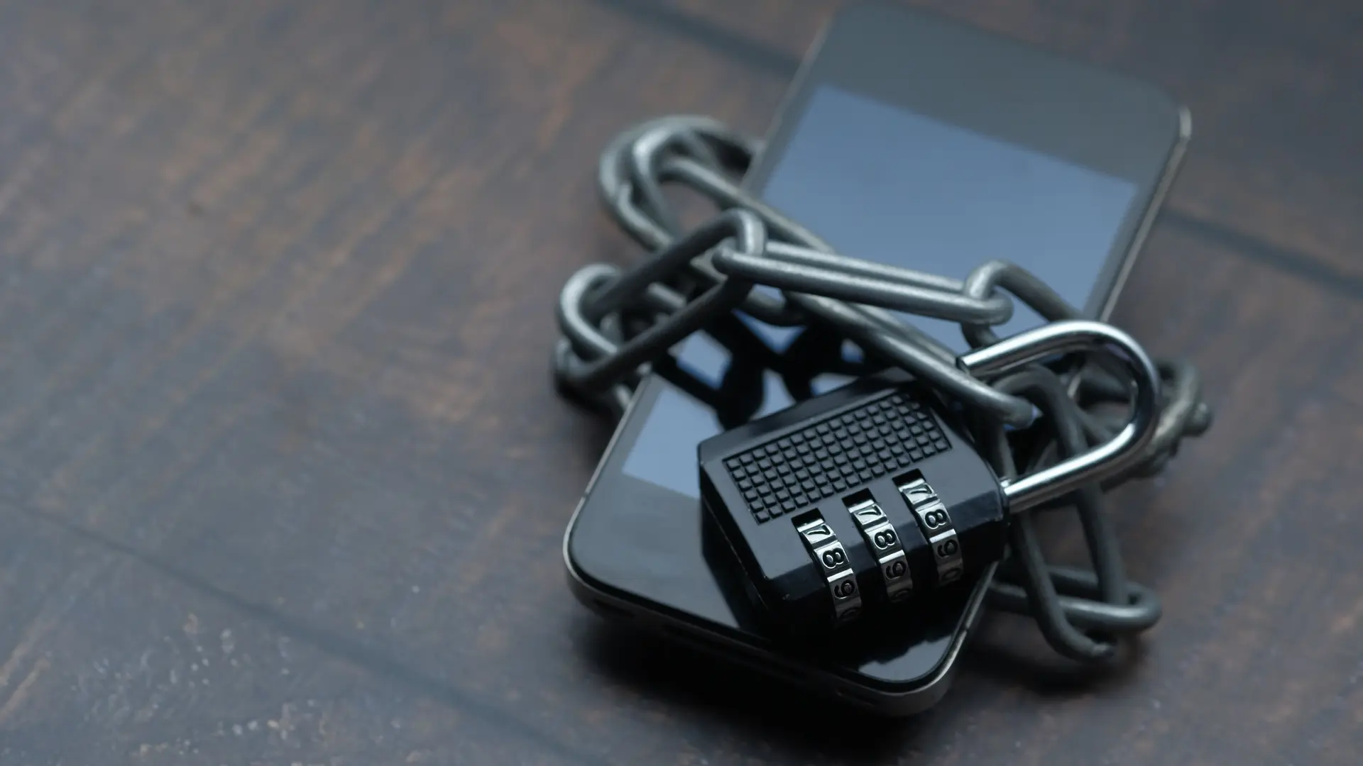 A smartphone wrapped with a chain and combination lock representing mobile account security